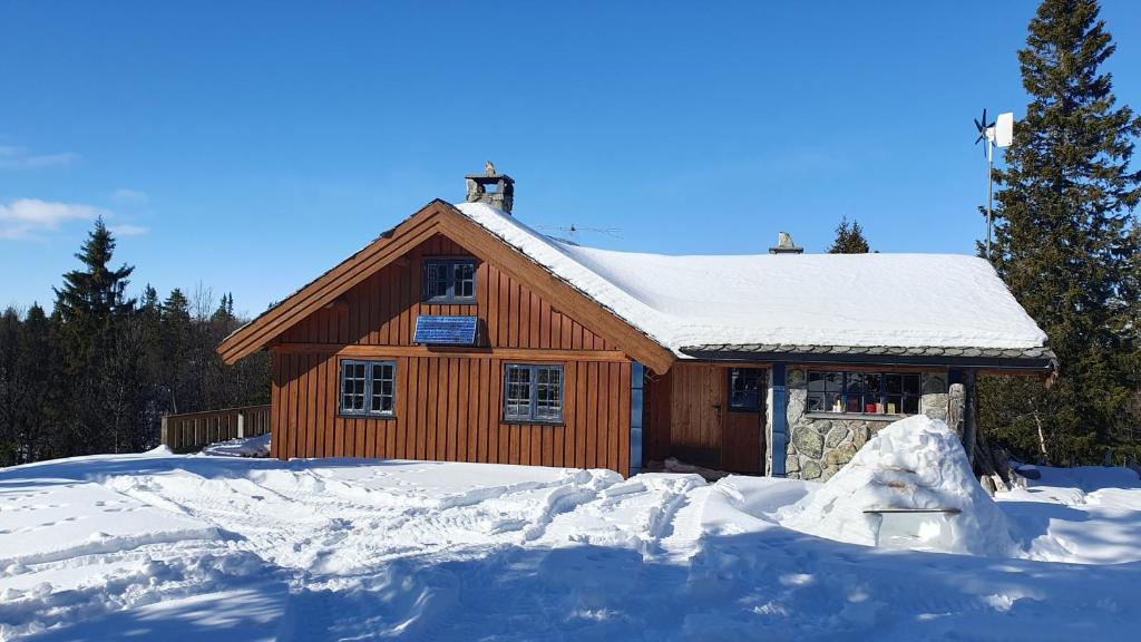 ein Blockhaus mit Schnee auf dem Boden vor dem Haus in der Unterkunft Cozy log cabin at beautiful Nystølsfjellet in Gol