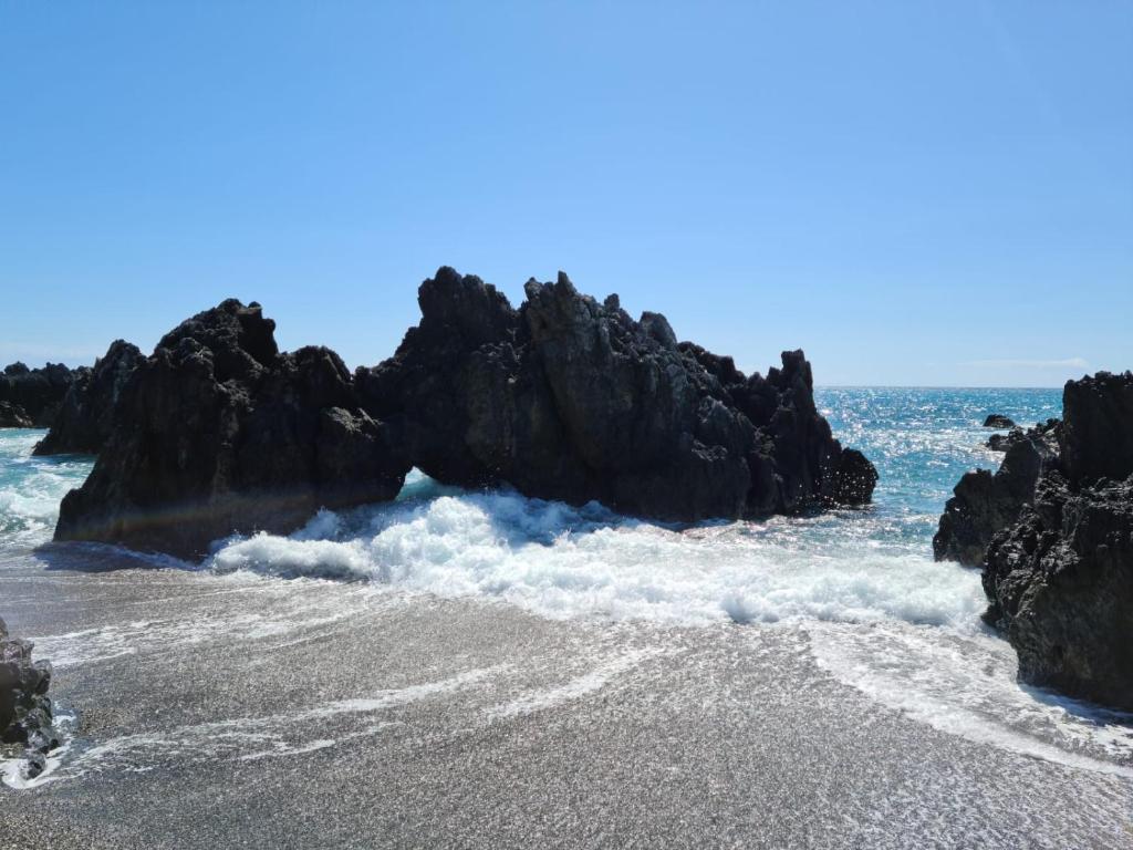 a beach with rocks in the water and the ocean at Fabian's luxury apartment in Scalea