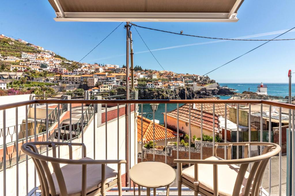 a balcony with two chairs and a view of the ocean at Casa das Andorinhas in Câmara de Lobos