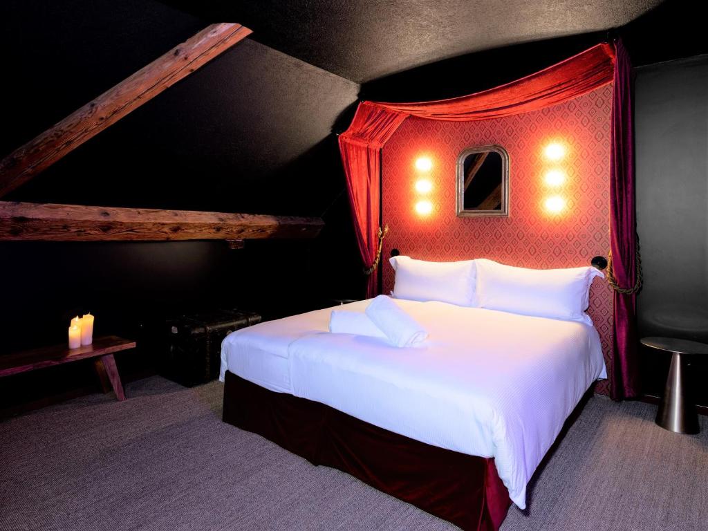 una camera da letto con un grande letto bianco con baldacchino rosso di Peanut Medieval Lodge a Saint-Ursanne