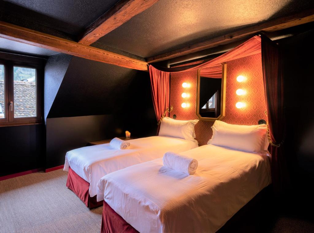 a bedroom with two beds with white sheets at Peanut Medieval Lodge in Saint-Ursanne