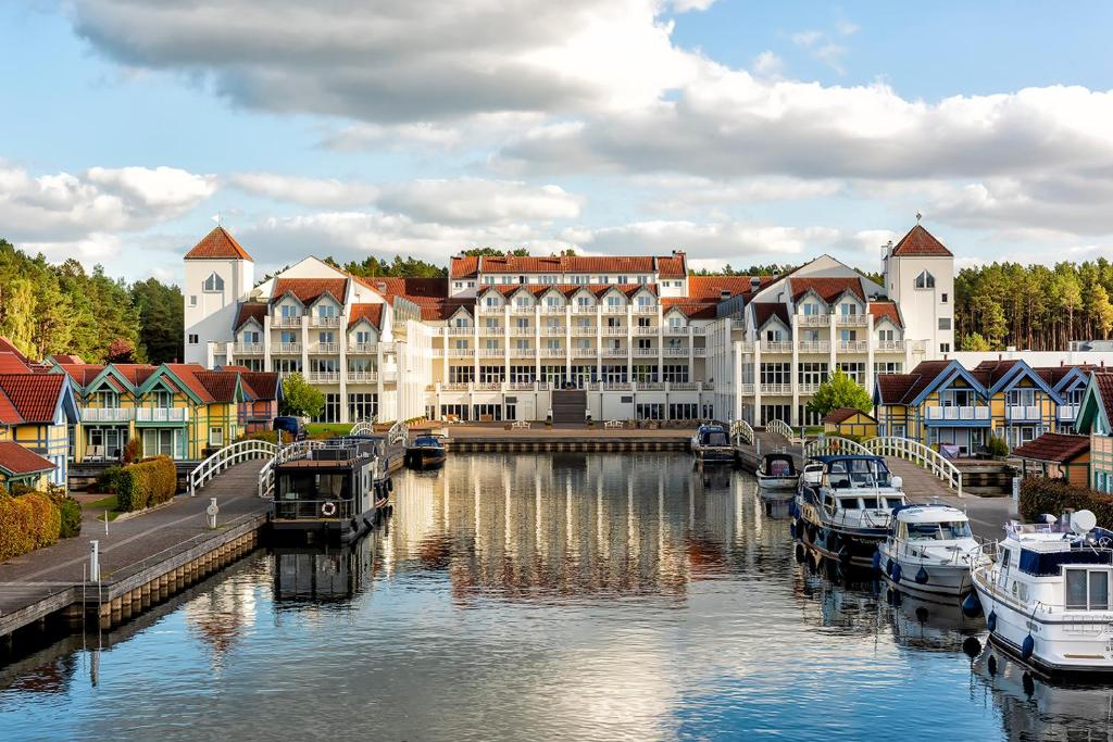 een stad met boten in een rivier met gebouwen bij Precise Resort Hafendorf Rheinsberg in Rheinsberg