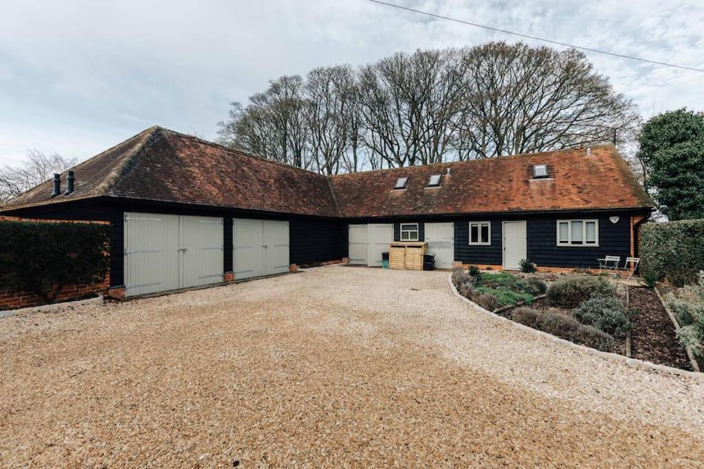 a large house with a garage on a gravel driveway at Hollyhock Lodge in Buckinghamshire