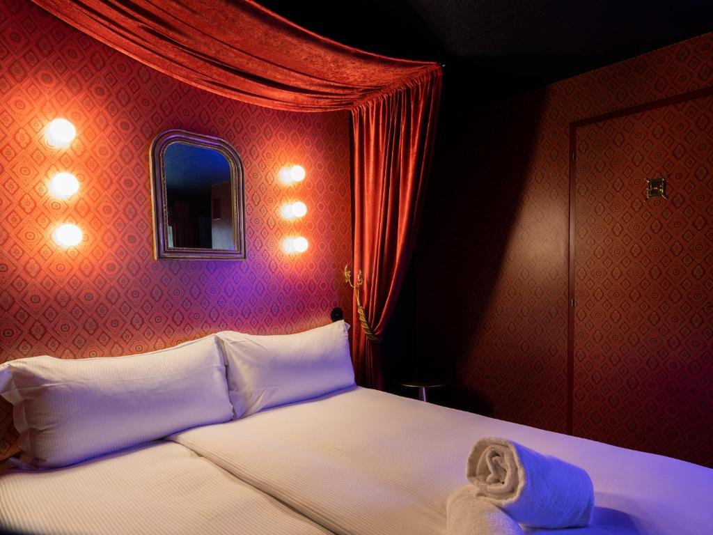 a bedroom with a white bed with a red wall at Peanut Medieval Lodge in Saint-Ursanne