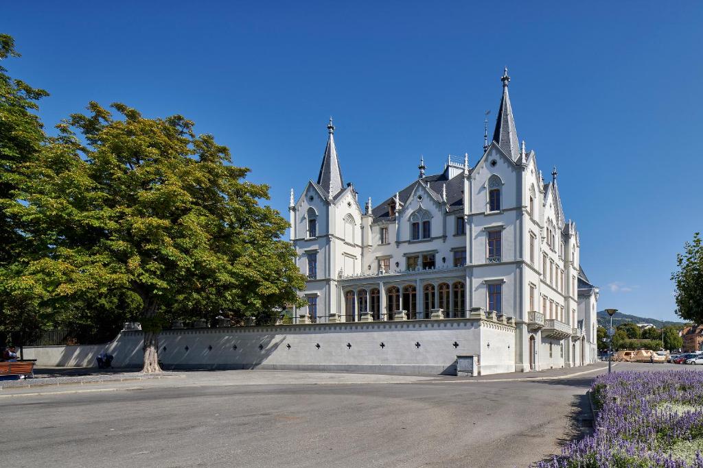 a large white house with a fence in front of it at Le Château de l'Aile in Vevey