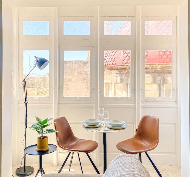 uma sala de estar com uma mesa, cadeiras e janelas em Designer Furnished - Entire Apartment Sliema 1B by Solea em Sliema