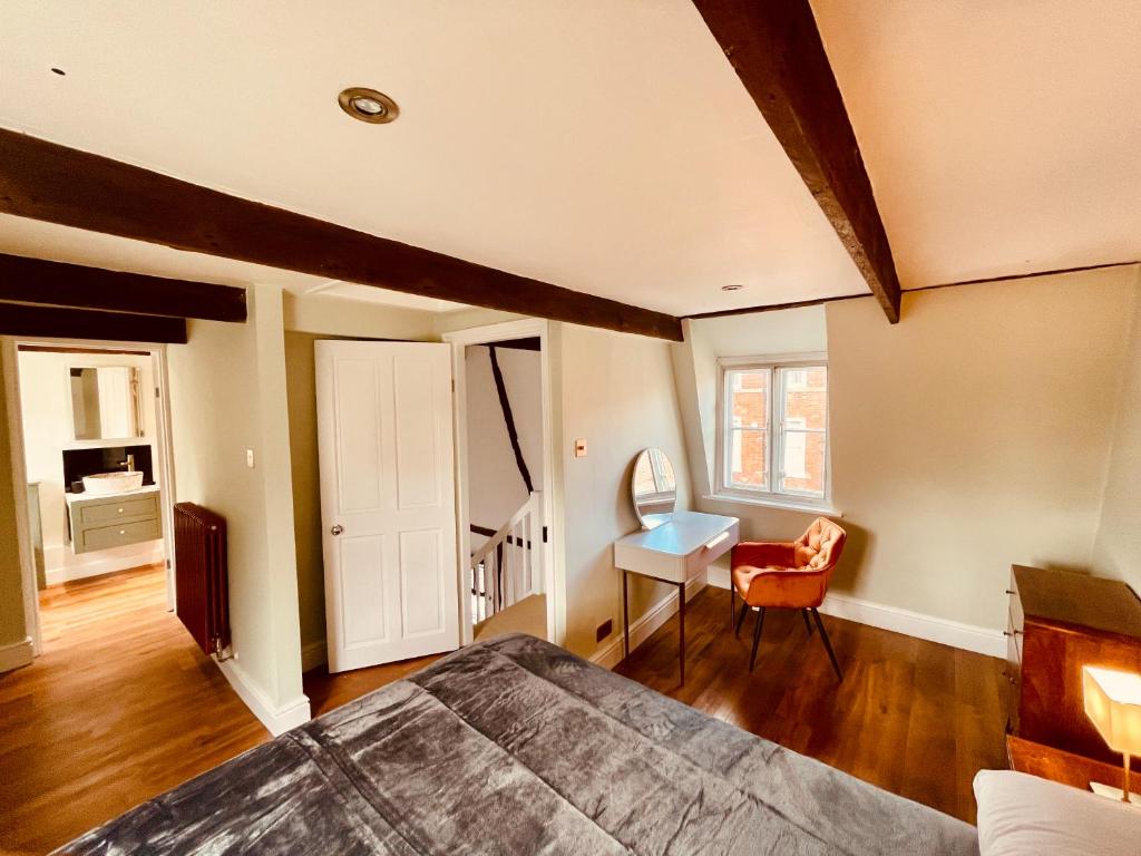 1 dormitorio con cama, escritorio y silla en Abbey Gardens Cottage, en Bury Saint Edmunds