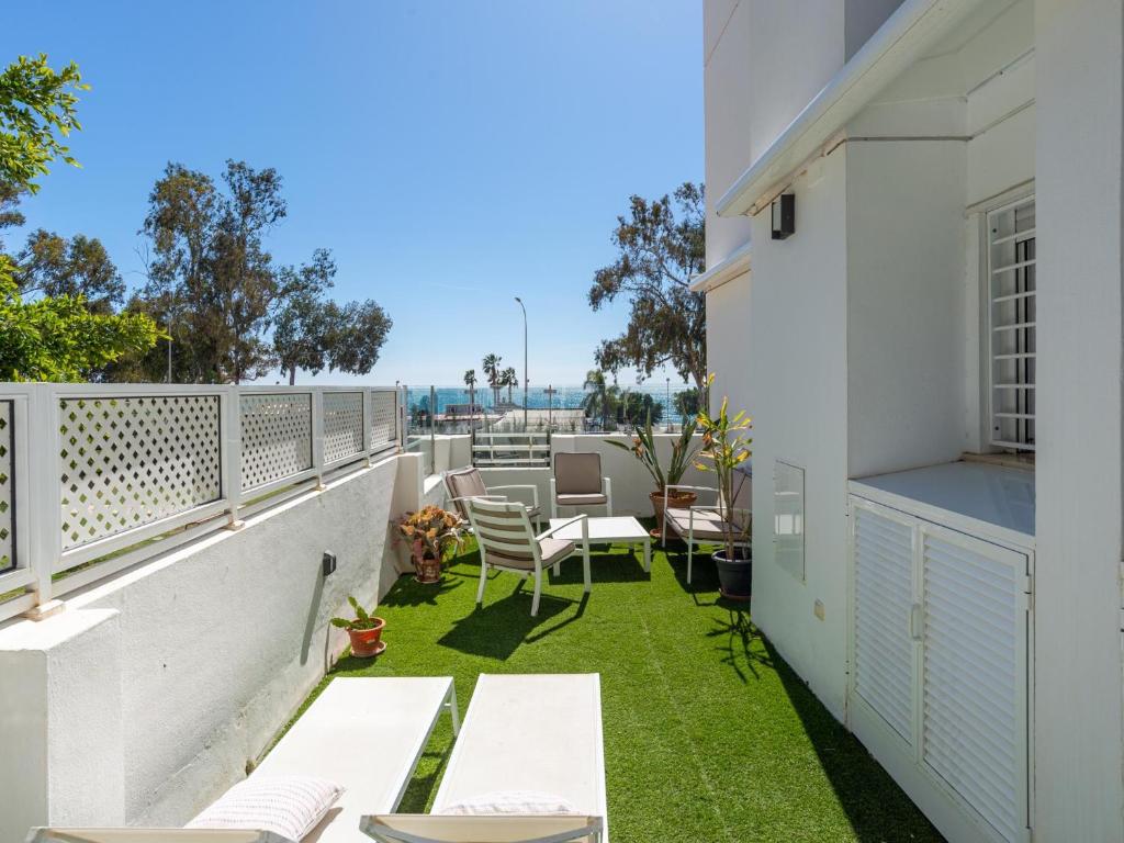 Elle comprend un balcon avec de l'herbe verte et un mobilier blanc. dans l'établissement Sea View with Parking by LU&CIA, à Malaga