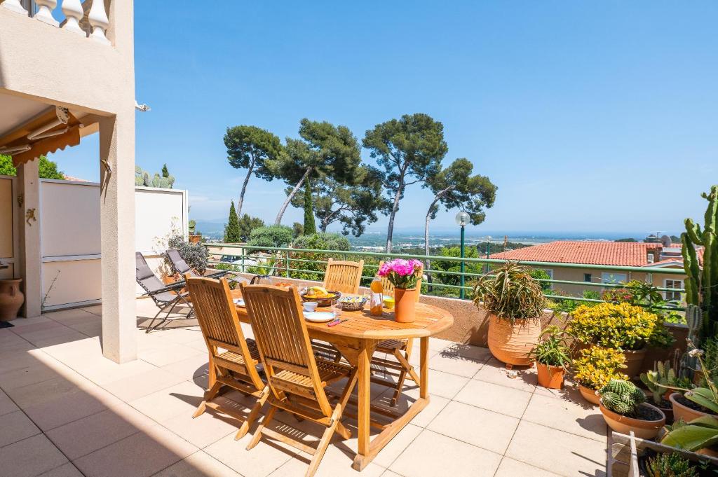 d'une terrasse avec une table et des chaises en bois sur un balcon. dans l'établissement La Clé Vue Mer, Clim, Terrasse, Parking à Hyères, à Hyères