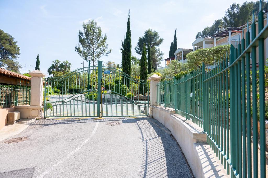 a green fence with a gate in a driveway at Costebelle Vue Mer 2ch&#47;4p Terrasse Garage privatif in Hyères