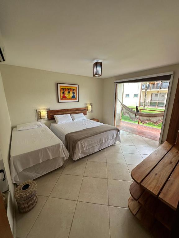 a bedroom with two beds and a large window at Apartamento na Vila La Torre in Porto Seguro