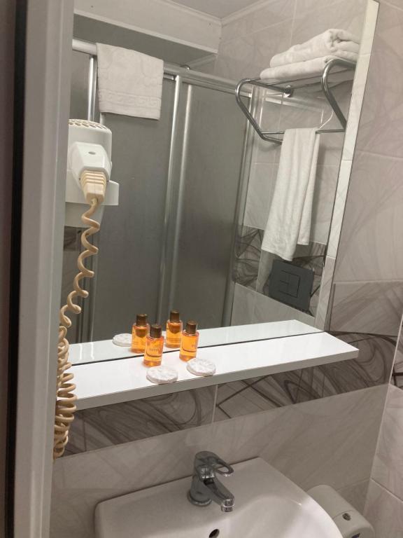 イスタンブールにあるホテル アイの洗面台の横の棚にガラス3枚が置かれたバスルーム