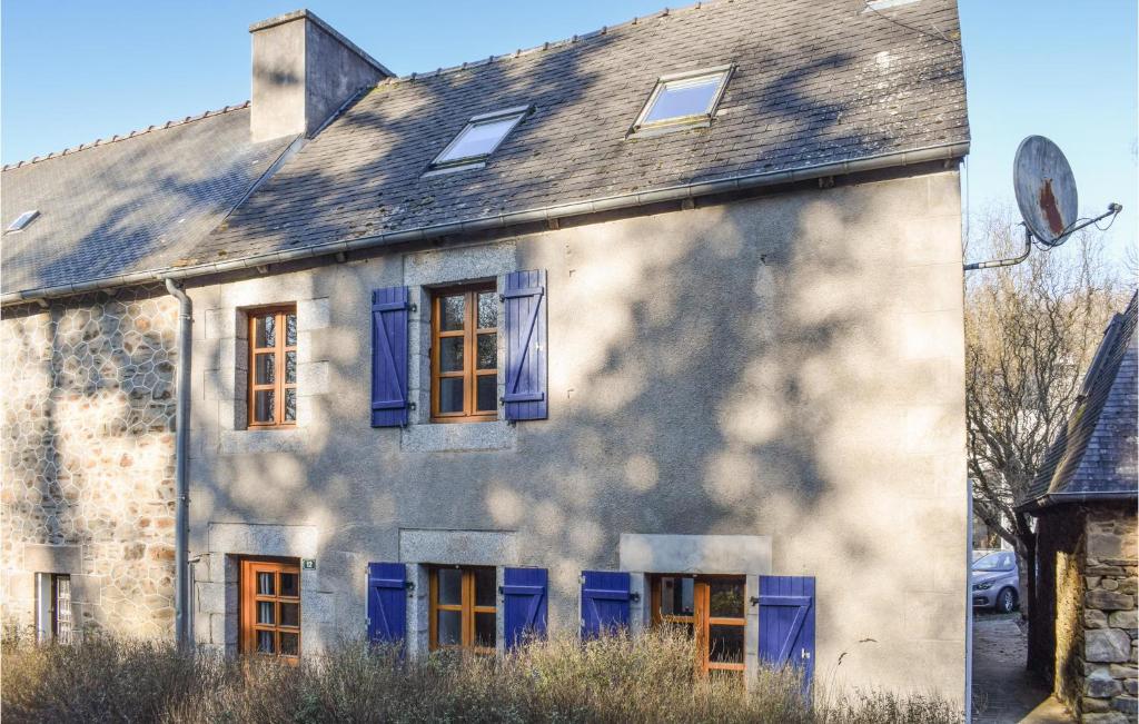une maison ancienne avec des fenêtres bleues et un toit dans l'établissement Lovely Home In Trmven With Wifi, à Trémeven
