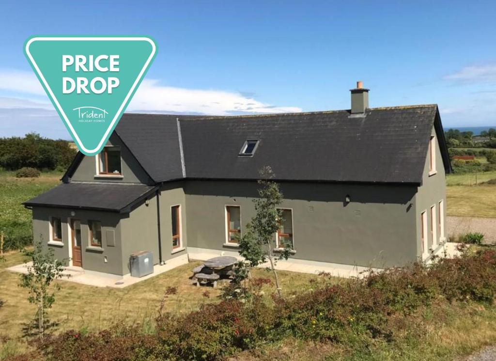 uma casa com um sinal de queda de preço em frente em Tinnaberna Lodge Kilmuckridge em Kilmuckridge