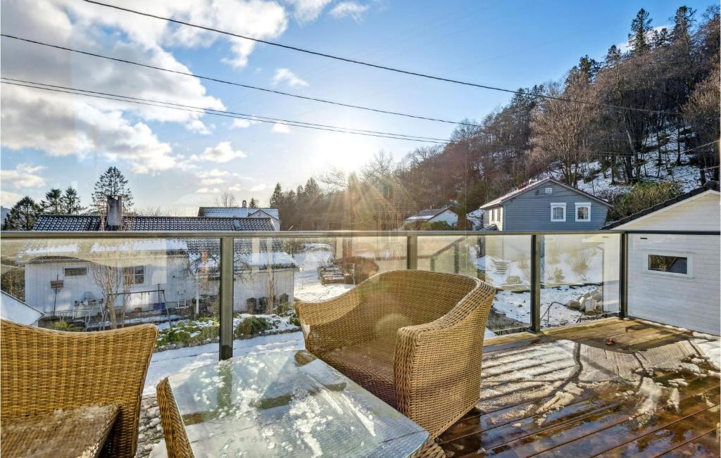 balkon z 2 krzesłami i szklanym stołem w obiekcie Beautiful Apartment In Nesttun With House A Panoramic View w Bergen