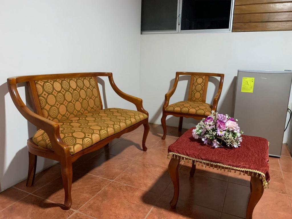 MY HOUSE IN MACAS, SUITE AMOBLADA في Macas: كرسيين وطاولة مع إناء من الزهور