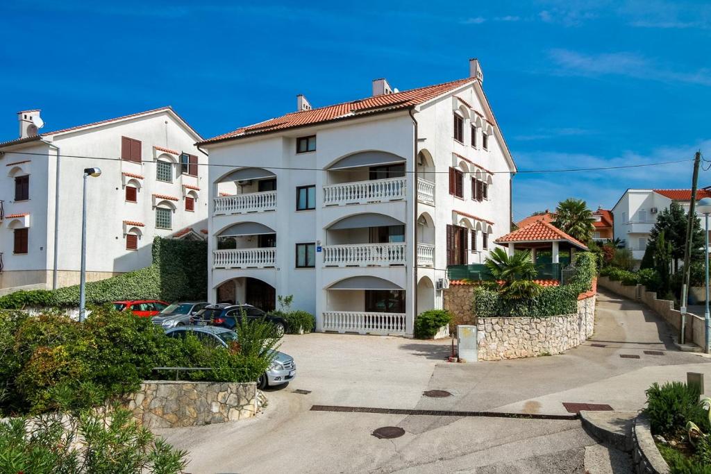 a large white apartment building with a parking lot at Apartments Katarina k in Malinska