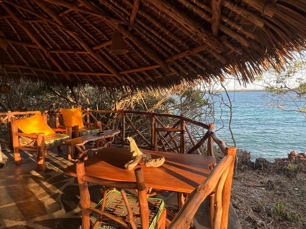 a resort with a table and chairs and the ocean at Bottle Cottage in Shimoni