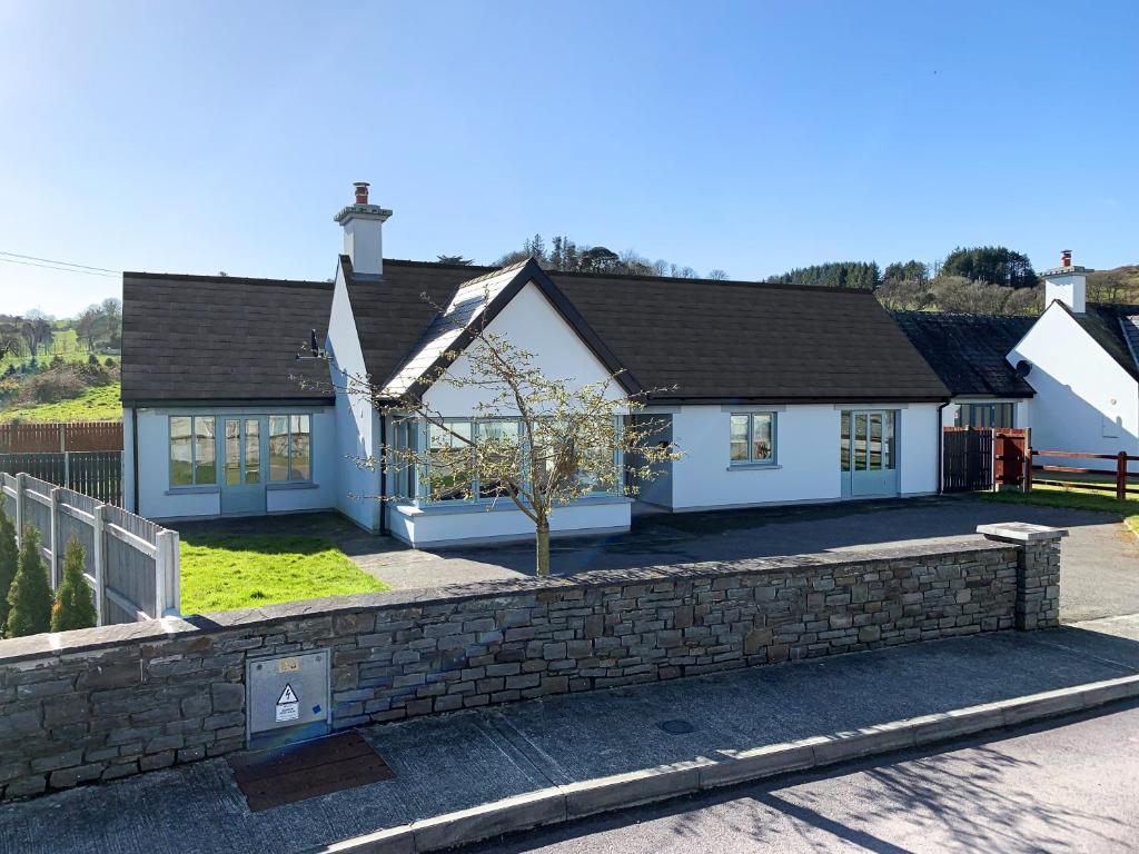 a white house with a brick retaining wall at 4 bedroom Holiday Home In Union Hall, West Cork in Union Hall