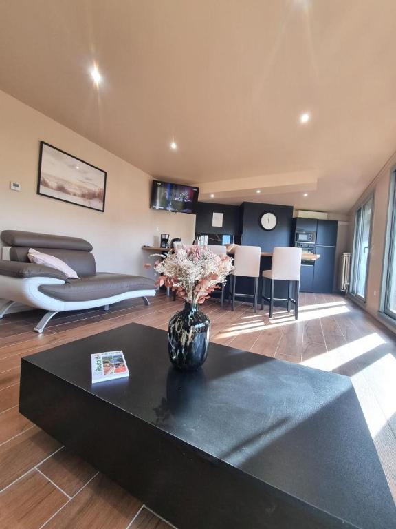 un salon avec un vase de fleurs sur une table dans l'établissement La petite plenitude, à Saint-Chamond