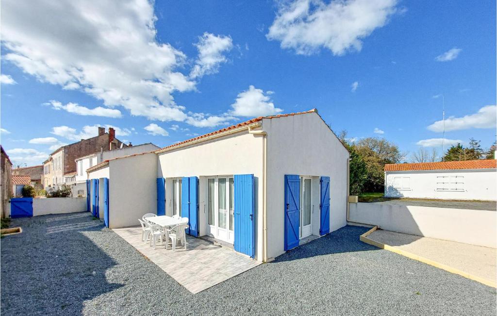 ein weißes Gebäude mit blauen Türen und einem Tisch in der Unterkunft Nice Home In Saint-georges-dolron With Kitchen in Saint-Georges-dʼOléron