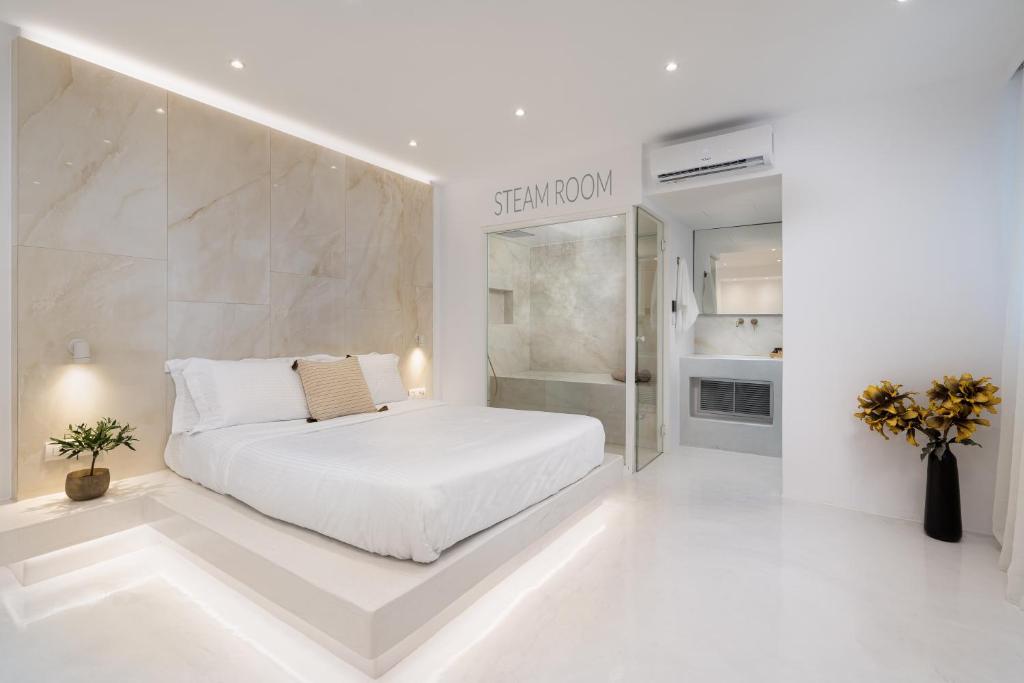 a white bedroom with a bed and a walk in shower at Cycladic Suites in Fira