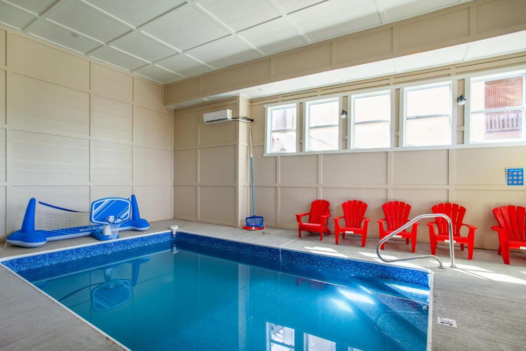a swimming pool with red chairs and a swimming pooliterator at Pool and Game Room in Stunning Mountain Cabin in Pigeon Forge