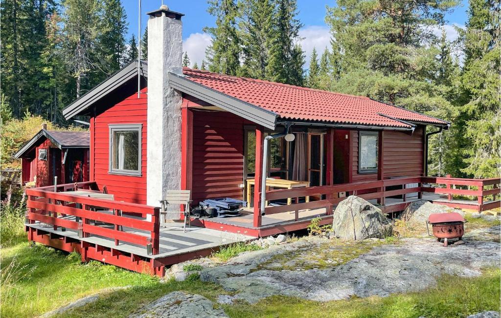 a red cabin with a large deck in the woods at 4 Bedroom Beautiful Home In Snertingdal 