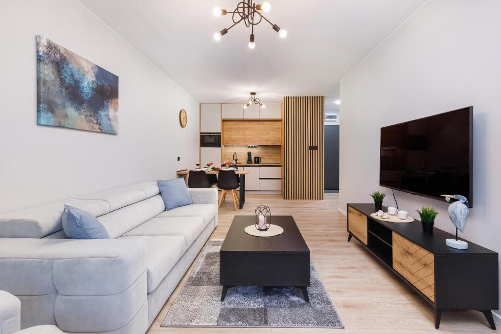 a living room with a couch and a tv at Dziwnów River Side Apartment with Balcony by Renters Prestige in Dziwnów