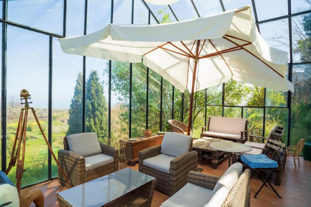 une maison en verre avec une table, des chaises et un parasol dans l'établissement Etnalodge, à Piedimonte Etneo