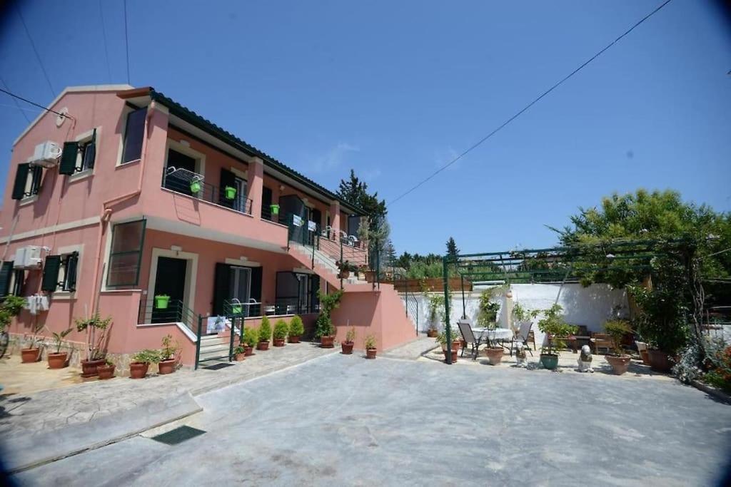 a pink building with potted plants in front of it at Filoxenia Apartments Corfu Rose in Alepou