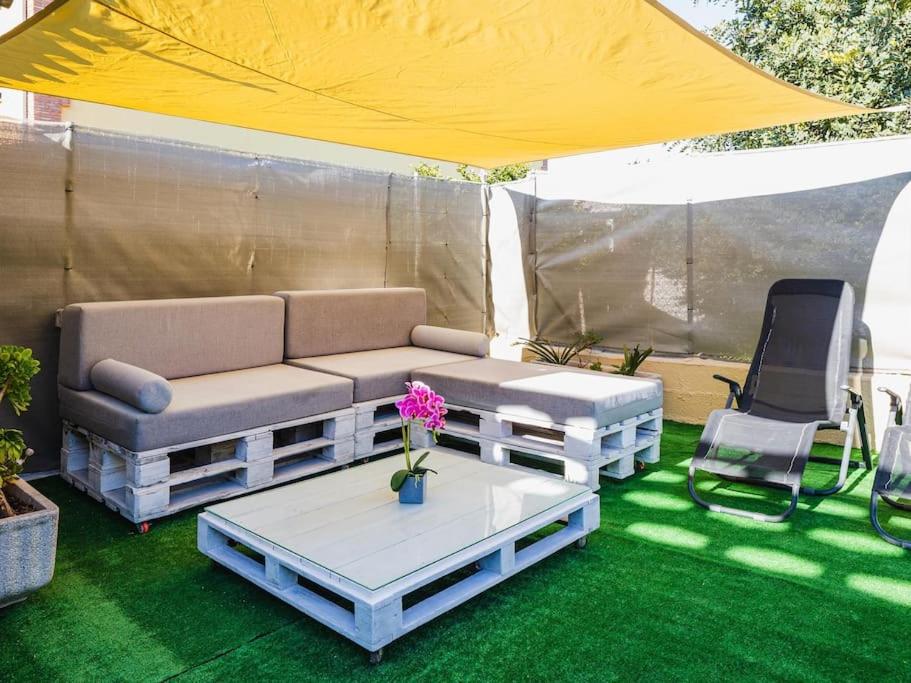 un sofá, una mesa y una silla debajo de una tienda en Casa con piscina a 5 min de la playa, en Burriana