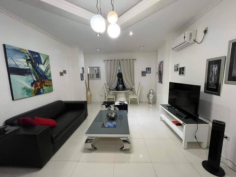 sala de estar con sofá negro y TV en Kandi big 1 BR, king bed, free housekeeping, Wi-Fi, en Ángeles