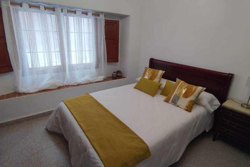 sypialnia z dużym białym łóżkiem z żółtymi poduszkami w obiekcie Casa Fernando y Maruja w mieście Pego