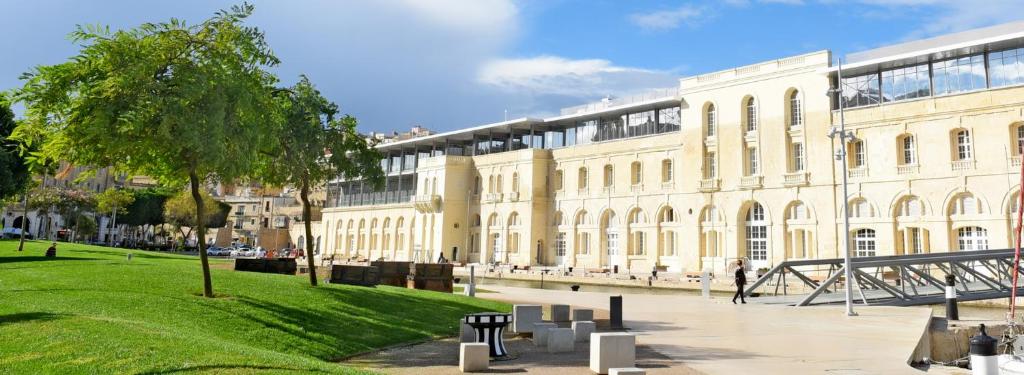 a large white building with a tree in front of it at Jessica Flat GuestHouse , Holiday and Business in Cospicua