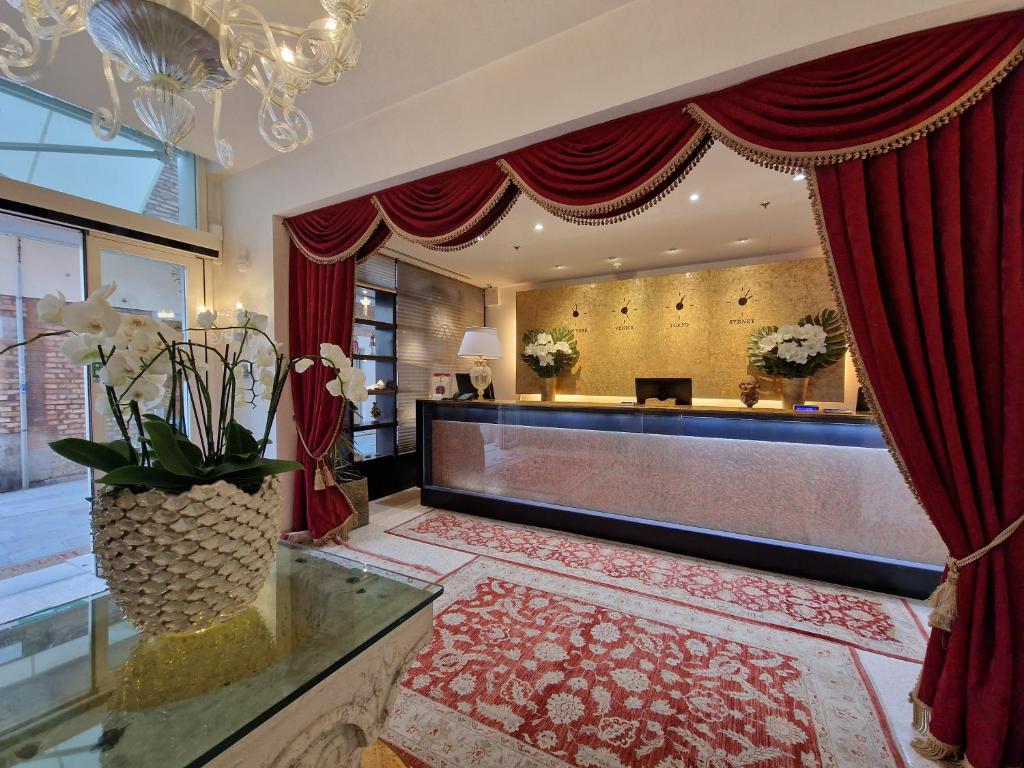 a hotel lobby with a reception desk and red curtains at Hotel A La Commedia in Venice