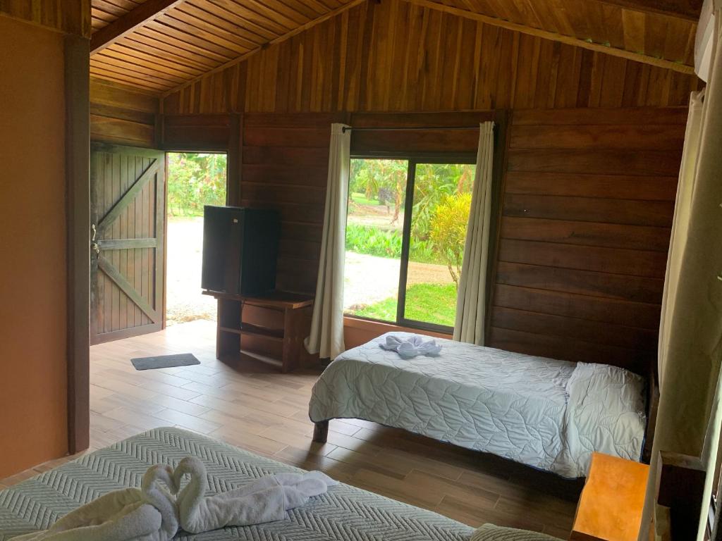 una camera da letto con due letti e una TV a schermo piatto di Cataratas Bijagua Lodge, incluye tour autoguiado Bijagua Waterfalls Hike a Bijagua