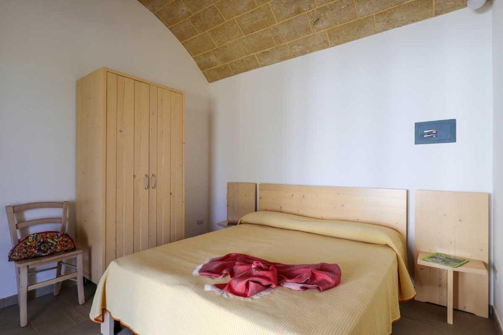 ein Schlafzimmer mit einem Bett mit einem roten Bademantel. in der Unterkunft Casina Spiggiano Agriturismo in Presicce