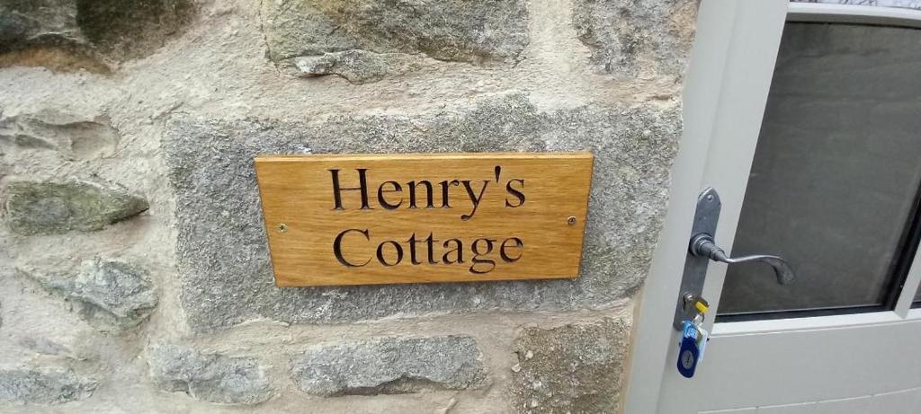 um sinal numa parede de pedra com as palavras "henneys cottage" em Henry's Cottage em Skipton