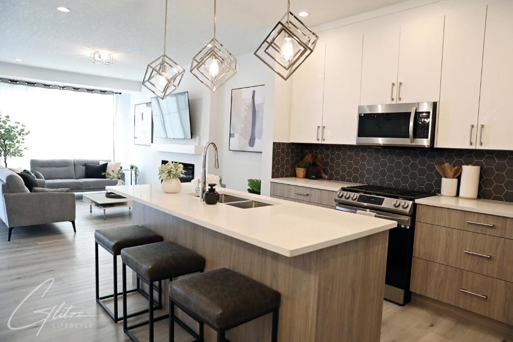 a kitchen with white cabinets and a kitchen island with bar stools at Modern Retreat 3 King Beds,Garage,Disney in Edmonton