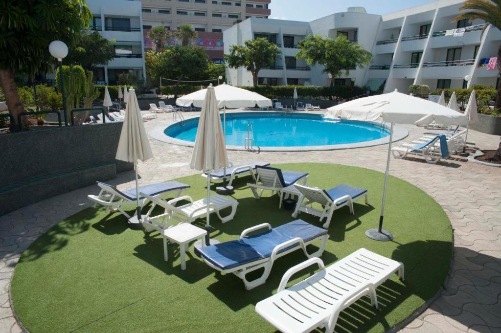 a pool with chairs and umbrellas and a group ofitures at Optimist las americas in Playa de las Americas