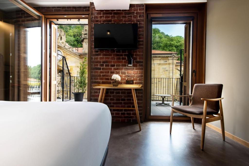 a room with a bed and a chair and a tv at Hotel Atari in Donostia-San Sebastián