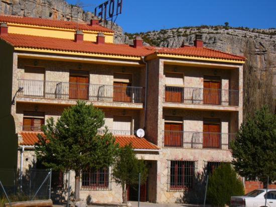 a large building with a red roof with a mountain at Hotel Restaurante Rio Cuervo in Vega del Codorno