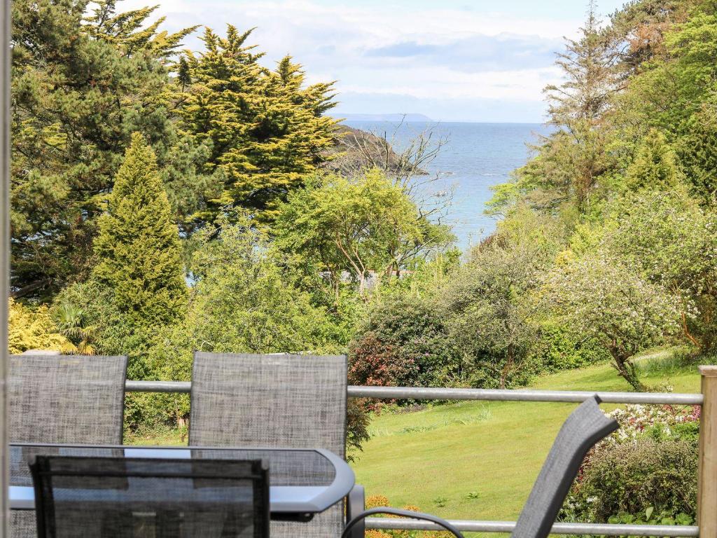 a table and chairs on a balcony overlooking the ocean at Flushing Meadow in Helston