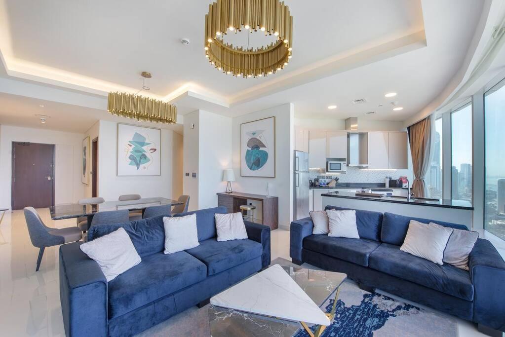 Superb Views & 36th Floor & Palm & Harbour View في دبي: غرفة معيشة مع أرائك زرقاء ومطبخ