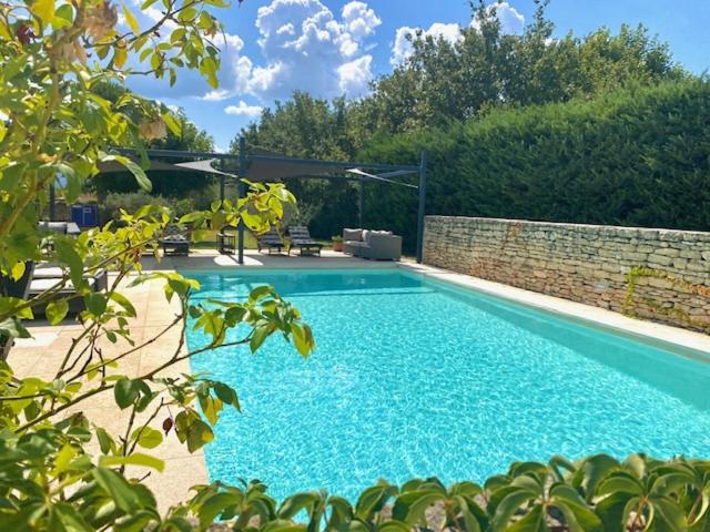 une grande piscine bleue à côté d'un mur en briques dans l'établissement Mas Oréa Sous la glycine, à Gordes