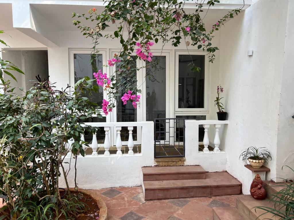 a porch with pink flowers and a white railing at Oceanic - Luxury Boutique Hotel in Palolem