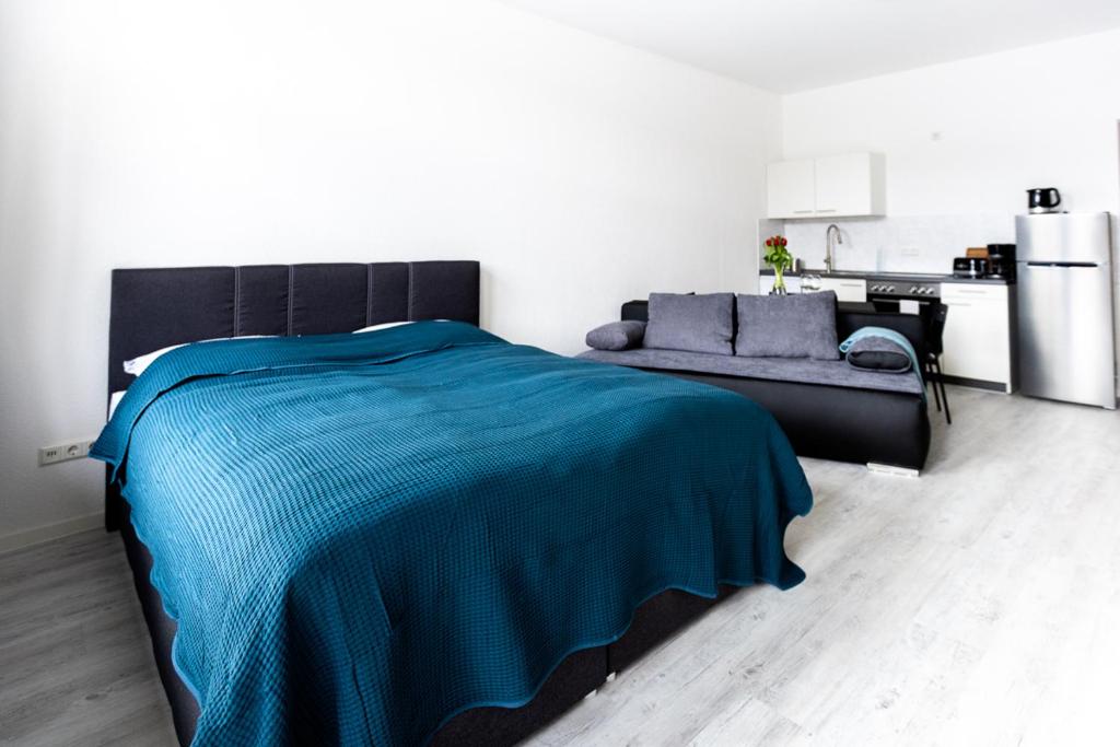 ein Schlafzimmer mit einem blauen Bett und einem Sofa in der Unterkunft Ferienwohnungen direkt am Werbellinsee in Joachimsthal