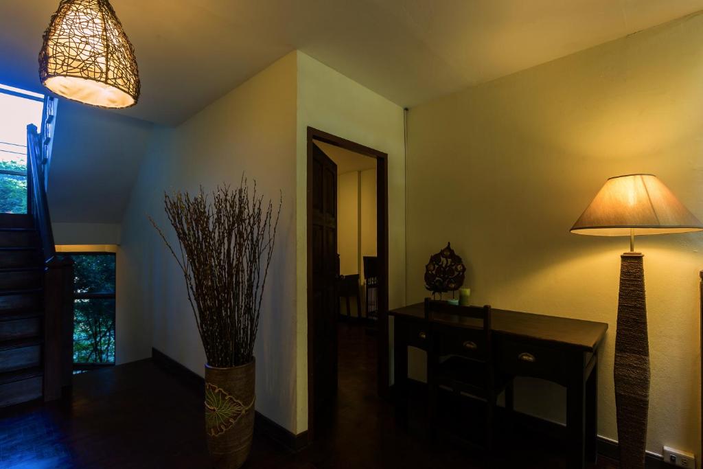 A dark wood writing desk sits in a softly lit room beside a doorway and tall window.