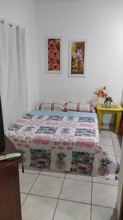 a bedroom with a bed with a quilt on the floor at 3 Kitnets in Rio das Ostras